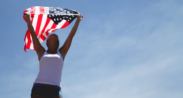 Young person holding american flag in the sky