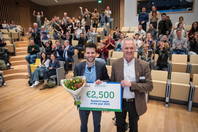 Ralph van Zwieten naast Dean of Research Wouter Hendriks met cheque en bloemen