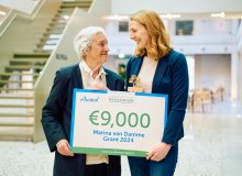 Marina van Damme en winnares Gesine Harms houden cheque vast en kijken elkaar aan