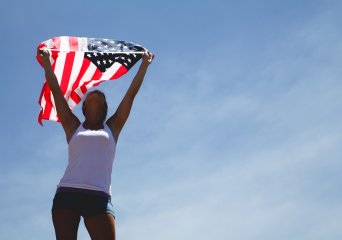 Young person holding american flag in the sky